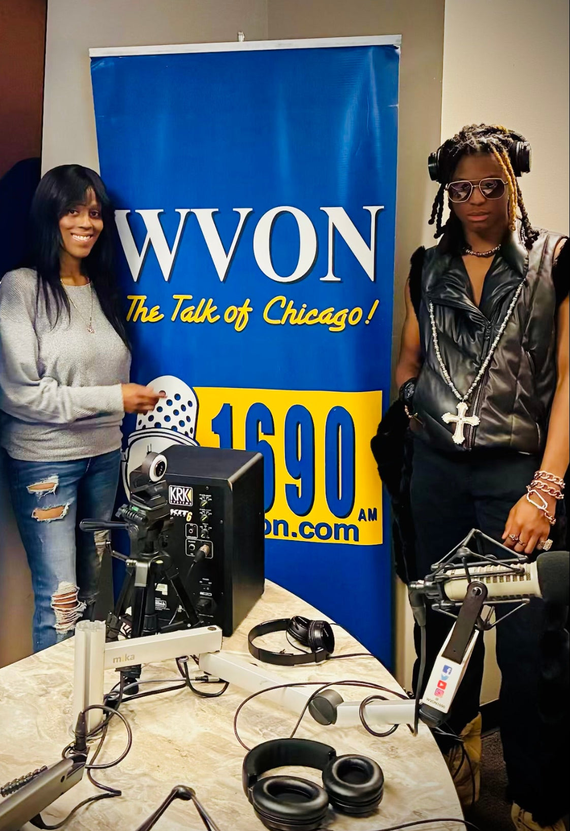 Two people standing in front of a WVON banner with broadcasting equipment on a table.