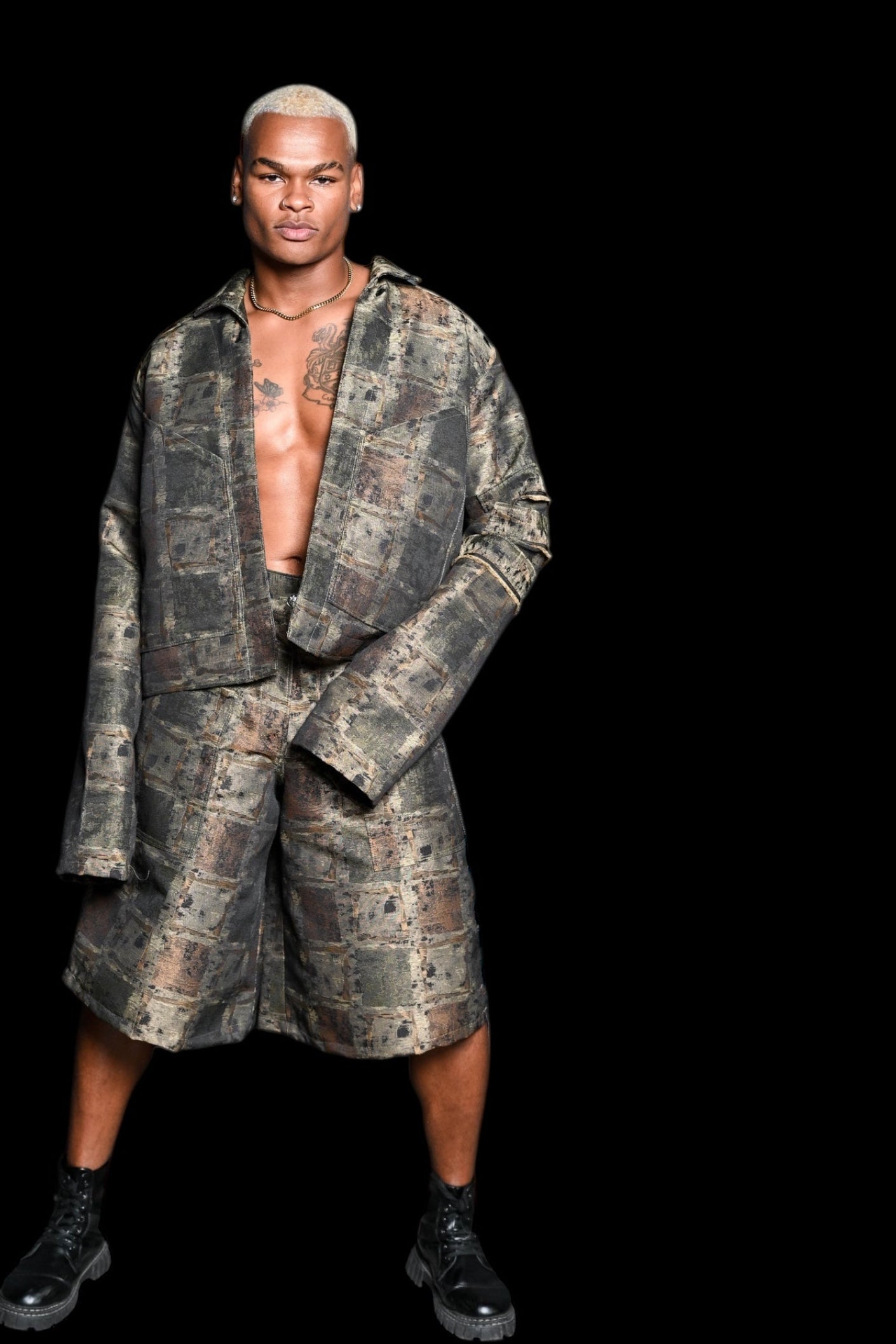 Male model wearing a camouflage outfit on a black background